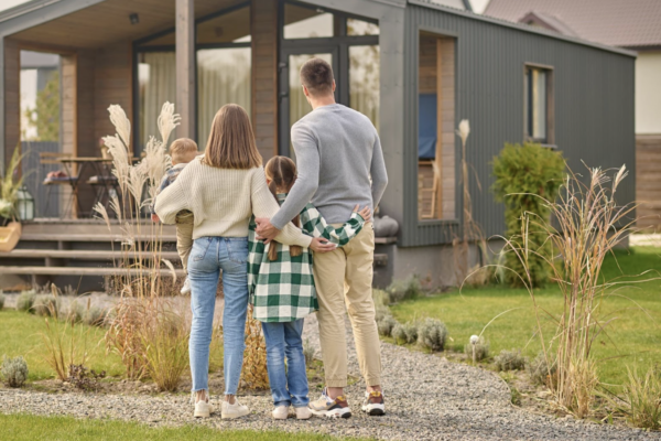 Photo back view of family hugging and admiring their home